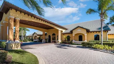 a large yellow house with a driveway at 8955 California Palm in Kissimmee
