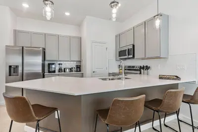 a kitchen with a large island in the middle with chairs at Brand New 5BedroomsPool LED At Paradiso Grande in Orlando