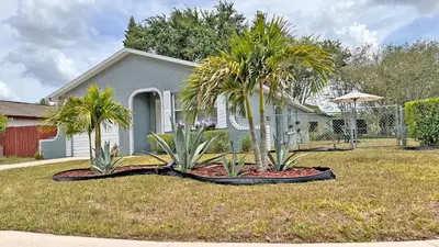 a house with two palm trees in a yard at Vacation Family Home - Close to Disney in Kissimmee