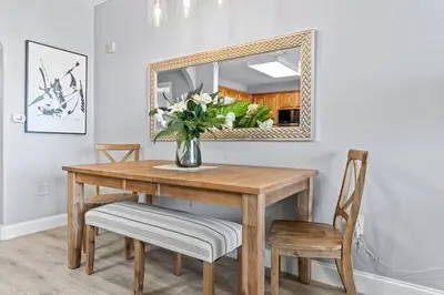a dining room table with a mirror and a vase with flowers at Cozy Lakeview Condo near Disney in Orlando