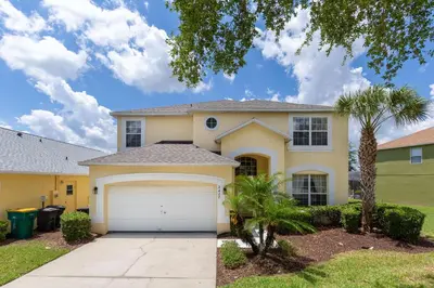 a house with a garage and a palm tree at Private Pool, Spa, Game Room & Theme Park Magic in Kissimmee