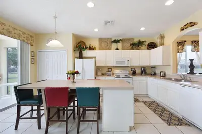 a kitchen with white cabinets and a table with chairs at Private Pool, Spa, Game Room & Theme Park Magic in Kissimmee
