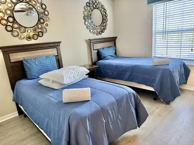 a bedroom with two beds with blue sheets and a mirror at Orlando Area Vacation Rental with private pool in Kissimmee