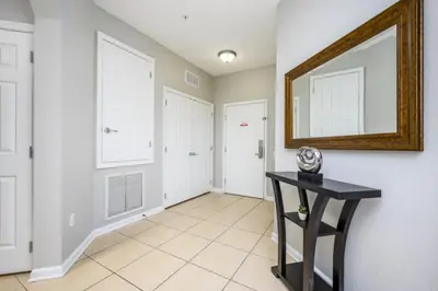 a hallway with white walls and a mirror and a table at Epic Universe New Listing Beautiful Vacation Condo - 3018 in Orlando