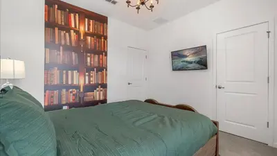 a bedroom with a bed and a book shelf with books at Upstay Family Home w Pool, Cinema & Games Room in Kissimmee