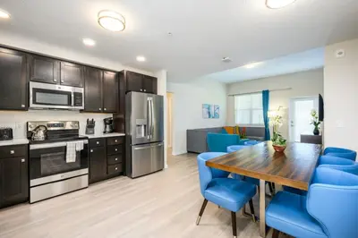 a kitchen and dining room with a wooden table and blue chairs at Brand New Modern Vista Cay Reserve Condo - 5003 in Orlando