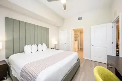 a bedroom with a large white bed and two chairs at Epic Universe Modern Vista Cay Condo - 5005 in Orlando