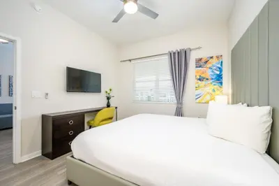 a white bedroom with a bed and a tv at New Modern Vista Cay Reserve Condo - 6003 in Orlando