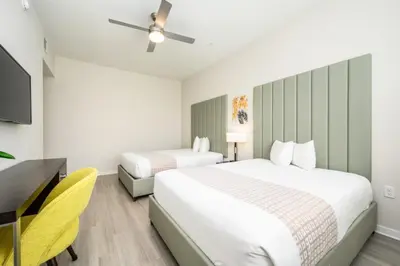 two beds in a room with a desk and a tv at New Modern Vista Cay Reserve Condo - 6003 in Orlando