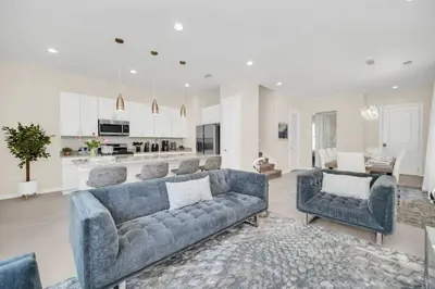a living room with blue couches and a kitchen at 5 BD 5BA Themed House Near Disney in Orlando