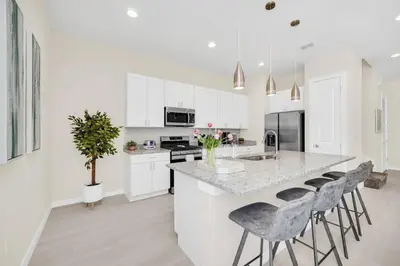 a kitchen with white cabinets and a island with bar stools at 5 BD 5BA Themed House Near Disney in Orlando