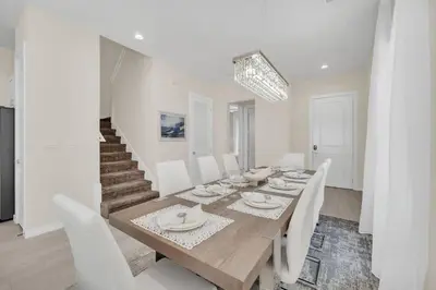 a dining room with a wooden table and white chairs at 5 BD 5BA Themed House Near Disney in Orlando