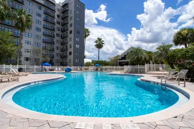 a swimming pool with chairs and a building at Cozy apt 2 bedrooms 1 mile Universal Studios in Orlando