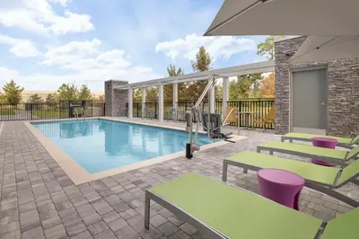 a swimming pool with tables and chairs next to a building at Home2 Suites By Hilton Sanford Orlando North in Sanford