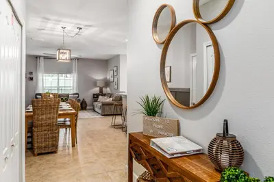 a dining room and living room with a mirror on the wall at Palms of Paradise! in Kissimmee