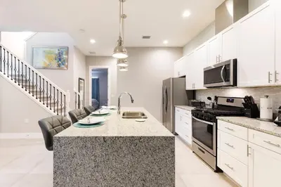 a kitchen with white cabinets and a counter top at Cozy Beautiful 5 Suites close to Disney World in Orlando