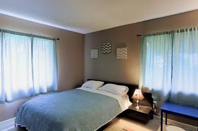 a bedroom with a bed and two windows with blue curtains at 3 Bed 2 Bath amazing Lakeview , Jacuzzi Bath Tub in Oviedo
