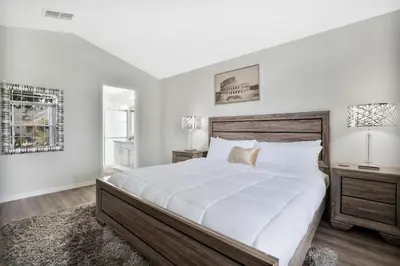 a white bedroom with a large bed and a window at Stunning Home Near Disney World in Orlando