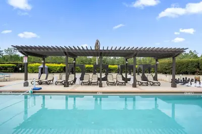 a swimming pool with chairs and a gazebo at Enchanted 4BR Family Style Townhome in Disney Area in Orlando