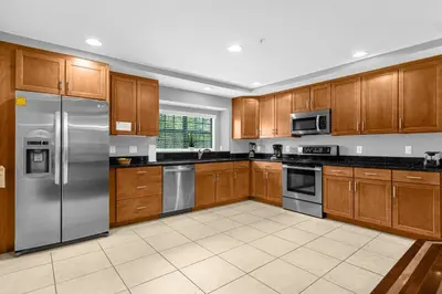 a kitchen with wooden cabinets and stainless steel appliances at Vibrant 4BR Family Townhome 1 mile from Disney World and Disney Springs in Orlando