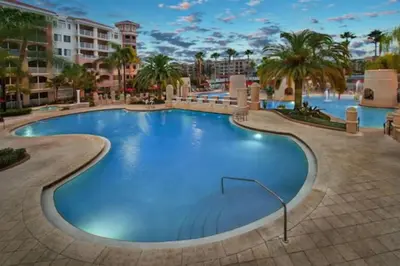 a pool at a resort with palm trees and buildings at Marriott Grande Vista Luxury 1BD villa sleeps 4 in Orlando