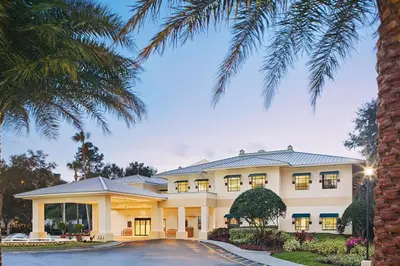 a large white house with a palm tree at Have fun in this 2BD condo in a resort setting with close access to Orlando parks in Orlando