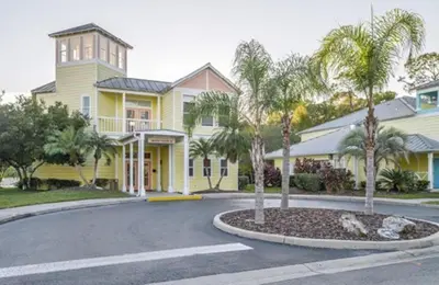 a yellow house with palm trees in the driveway at Diamond Barefootn Resort 2BD in Orlando
