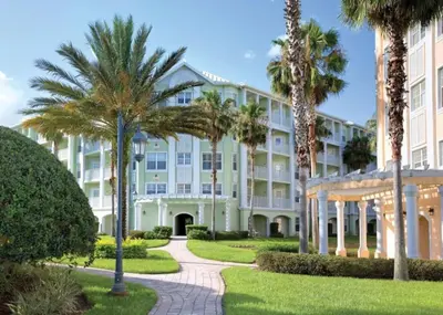 a large white building with palm trees and a pathway at WorldMark Kingstown Reef - 2BD Sleeps up to 6 in Orlando