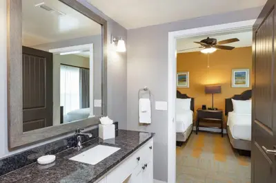 a bathroom with a sink and a mirror and a bedroom at WorldMark Kingstown Reef - 2BD Sleeps up to 6 in Orlando
