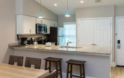 a kitchen with a counter and some stools in it at Enjoy Orlando Family Getaway in 2BD condo with lots of onsite activities in Orlando