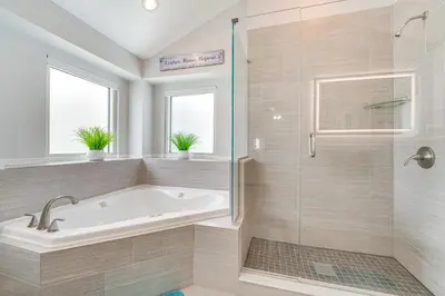 a bathroom with a tub and a glass shower at 5 Mi to Disney World Spacious Kissimmee Home! in Kissimmee