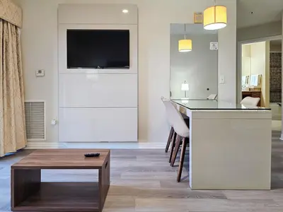 a living room with a table and a tv on a wall at 1 Bedroom - Grand Suite 5 min to Universal, I-drive & Outlets in Orlando