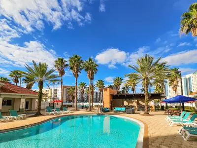 a swimming pool with palm trees and chairs at 1 Bedroom - Grand Suite 5 min to Universal, I-drive & Outlets in Orlando