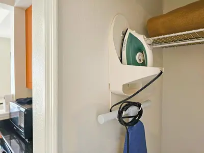 a iron hanging on a wall next to a closet at Double King Bed Suite, 5 Min from Universal, I-Drive & Outlets in Orlando