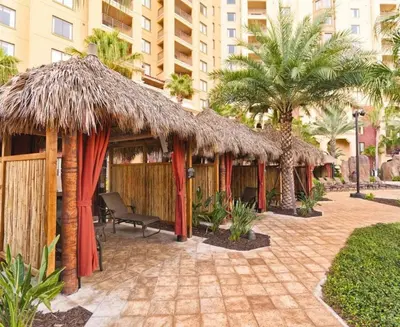 a row of huts with palm trees and a building at Beautiful Resort in Bonnet Creek 2BD Deluxe near Walt Disney World in Orlando