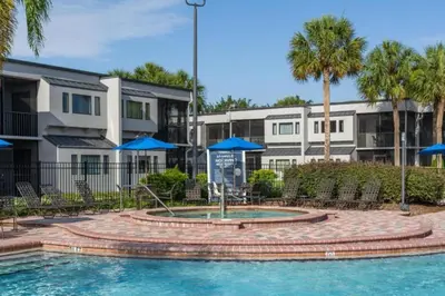 a pool with blue umbrellas in front of condos at Diamond - Orbit One Vacation Villas- 2BD in Orlando