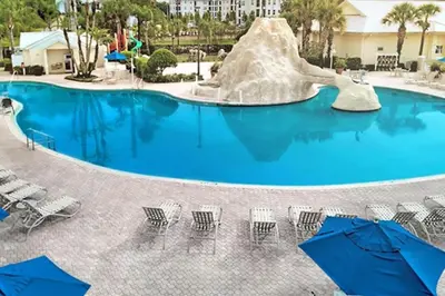 a swimming pool with a slide and chairs and umbrellas at Diamond - Cypress Pointe Resort - St in Orlando