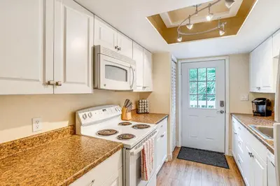 a kitchen with white cabinets and a stove at Half-Mi to Riverwalk Charming Sanford Retreat! in Sanford
