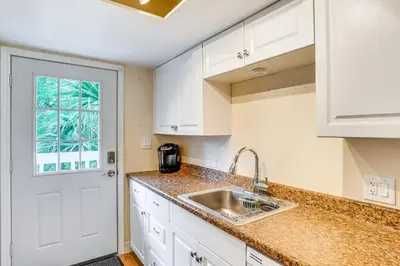 a kitchen with white cabinets and a sink and a window at Half-Mi to Riverwalk Charming Sanford Retreat! in Sanford