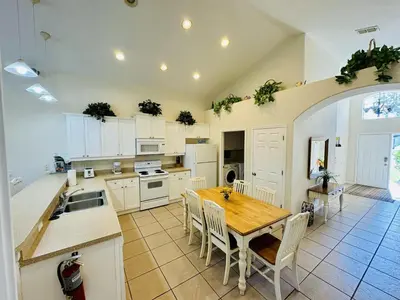 a kitchen with a wooden table and white cabinets at 43 Vacation Home With Private Pool Located At Formosa Gardens!! in Orlando