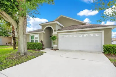 a house with a garage and a tree at Relaxing Retreat with Pool and Movie Theater in Orlando