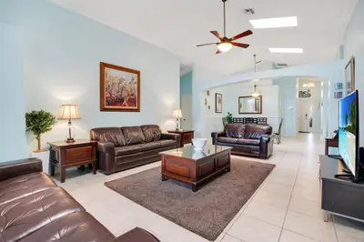 a living room with leather furniture and a flat screen tv at Relaxing Retreat with Pool and Movie Theater in Orlando