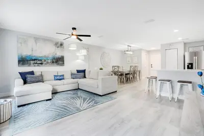 a living room with a white couch and a kitchen at Stylish Villa Near Disney & Universal in Kissimmee