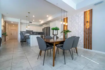 a kitchen and dining room with a wooden table and chairs at Stylish 2-BR Apt Sleeps 7 Near Disney Magic in Kissimmee