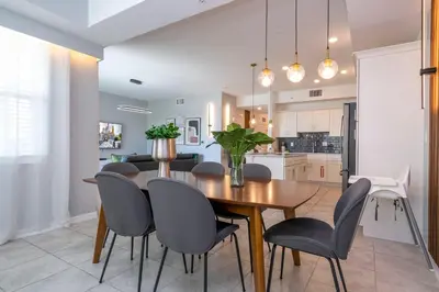 a kitchen and dining room with a wooden table and chairs at Stylish 2-BR Apt Sleeps 7 Near Disney Magic in Kissimmee