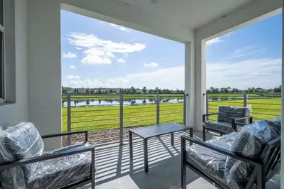 a balcony with chairs and a table and a view of a field at Stylish 2-BR Apt Sleeps 7 Near Disney Magic in Kissimmee