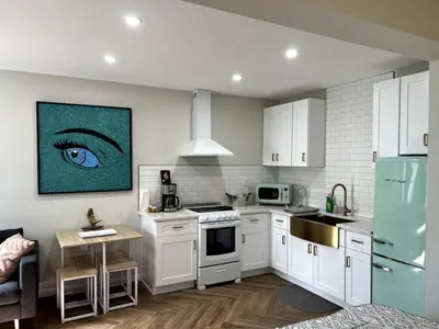 a kitchen with white cabinets and a blue eye on the wall at Downtown Groovy Studio in Orlando