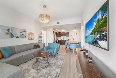 a living room with a gray couch and blue chairs at Modern Resort 2BR near Icon park, Convention center and NEW Epic Universe in Orlando
