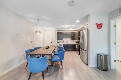 a kitchen and dining room with a table and blue chairs at Modern Resort 2BR near Icon park, Convention center and NEW Epic Universe in Orlando