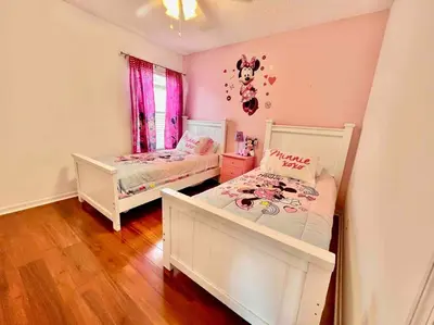 two beds in a bedroom with pink walls and wooden floors at 7BD 5BA w Pool Spa Home 10 mins away to Disney in Kissimmee